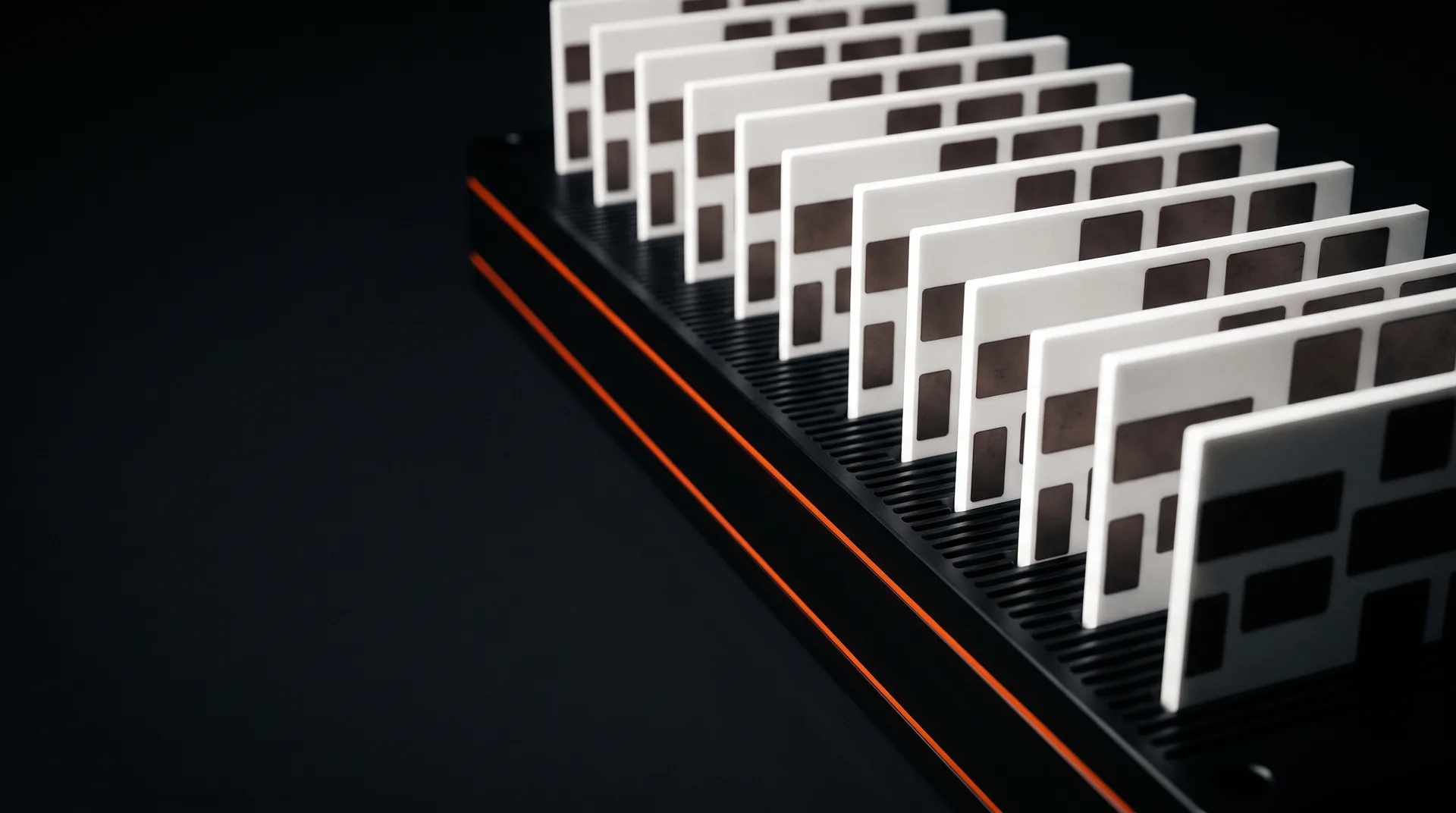 A row of white alumina power electronics substrates with dark bonded copper islands standing on a black cold plate